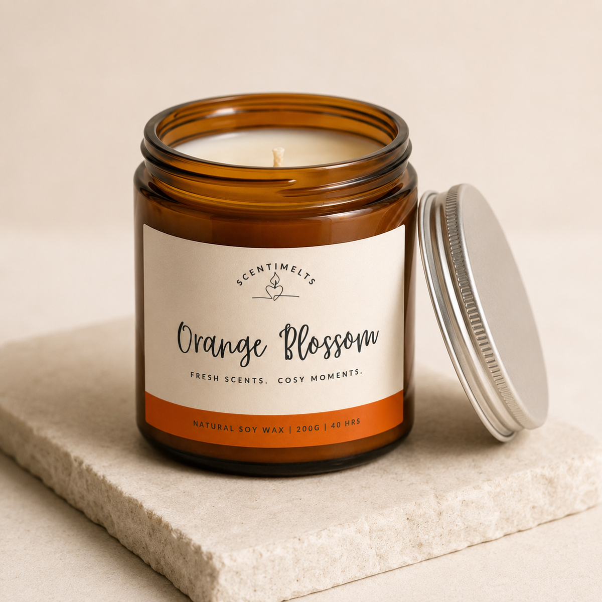 Scentimelts Orange Blossom candle in an amber jar with a white label on a beige surface