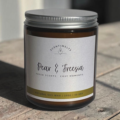 Candle jar labeled 'Pear & Freesia' by Scentimelts on a wooden surface.