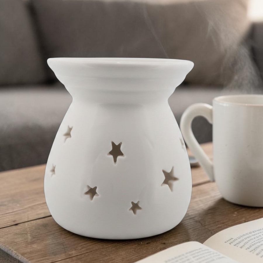 White ceramic wax melt burner with star cut-outs styled on a wooden table