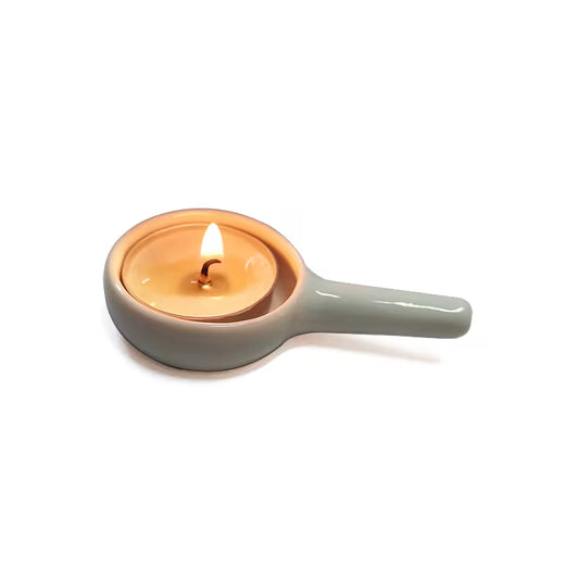 White ceramic tealight candle holder with a lit candle